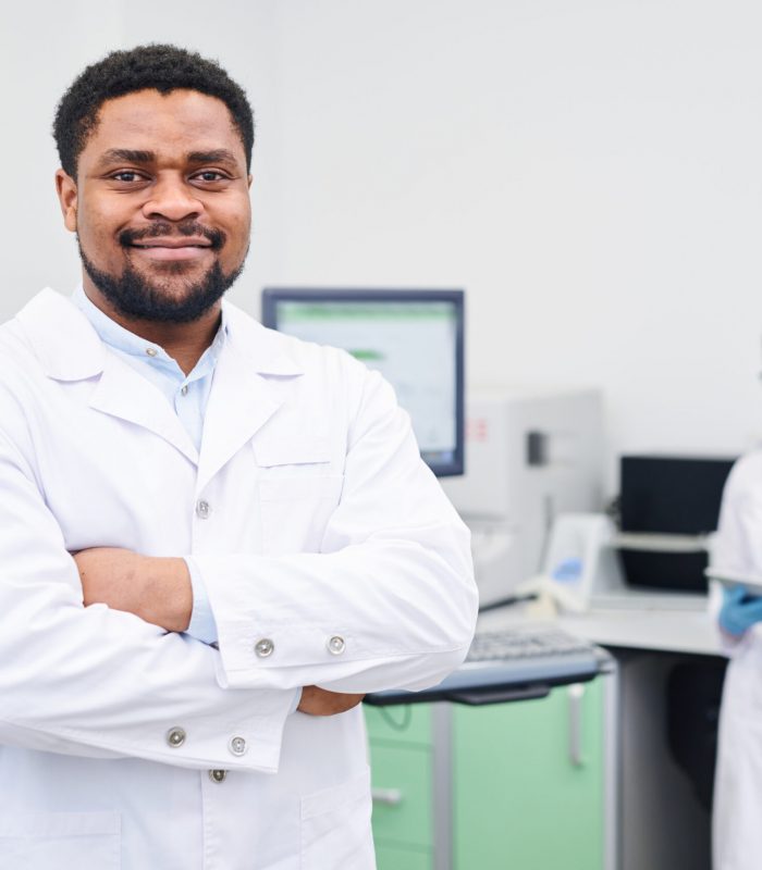 Content confident experienced handsome young African-American medical scientist with beard crossing arms on chest and looking at camera